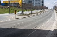 an empty street with cars driving down it and tall buildings in the background across the road