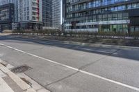 a empty road with multiple skyscrapers in the background and there is an empty street to the right of it