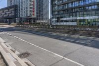 a empty road with multiple skyscrapers in the background and there is an empty street to the right of it