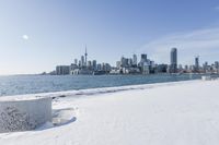 a snowy beach and the city skyline in the background in toronto, ontario canada, as seen from the frozen lakefront