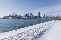 a snowy beach and the city skyline in the background in toronto, ontario canada, as seen from the frozen lakefront