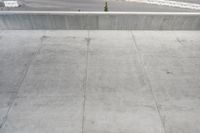 an asphalted street with snow and concrete walling, including a skateboard ramp