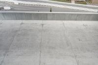 an asphalted street with snow and concrete walling, including a skateboard ramp