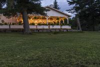 the front porch of a cottage at dusk with fairy lights strung on it's windows