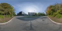 a 360 - view of the intersection with the sun shining over some buildings with trees in front