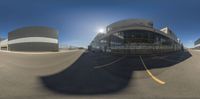 a fish eye lens image of an airport with the sun shining on the ground and a few large buildings