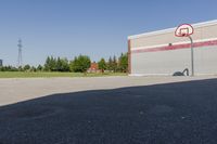 a basketball hoop at top of an empty lot by a building, as seen in a photo