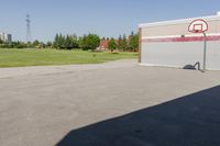 a basketball hoop at top of an empty lot by a building, as seen in a photo