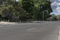 an empty street with white lines on both sides and trees on either side of the street