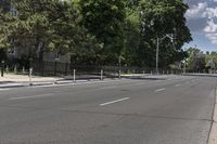 an empty street with white lines on both sides and trees on either side of the street