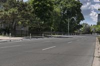 an empty street with white lines on both sides and trees on either side of the street