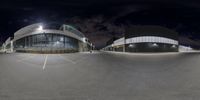 a wide angle view of a sports stadium at night and full of lights with no people around