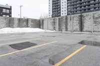 the empty parking lot has only snow on the ground in front of an old brick factory