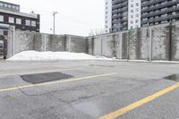 the empty parking lot has only snow on the ground in front of an old brick factory