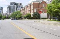 a stop sign at an intersection of an empty street next to some high rise buildings