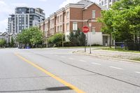 a stop sign at an intersection of an empty street next to some high rise buildings