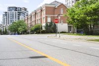 a stop sign at an intersection of an empty street next to some high rise buildings