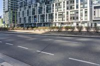 the buildings are on either side of a road with trees in the street between them