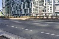 the buildings are on either side of a road with trees in the street between them