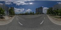 a 360 - angle photograph of the highway through the city on a cloudy day, with high rise buildings in the distance