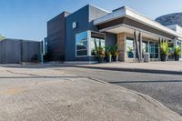 the entrance to a motel with red brick sidewalk and large windows, and landscaping on the side