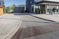 the entrance to a motel with red brick sidewalk and large windows, and landscaping on the side