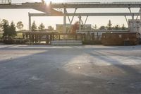 the sun is setting over the empty parking lot next to the train station and some vehicles