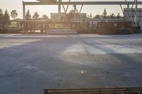 the sun is setting over the empty parking lot next to the train station and some vehicles