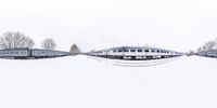 two trains that are sitting on a snowy ground area next to trees in the background