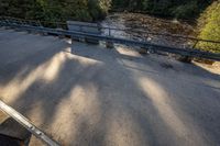 a bench sits beside a large river, and a wooden deck is overlooking the forest