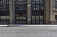 a brick building has many windows with large windows, a black wrought rail, and a white parking sign