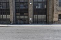 a brick building has many windows with large windows, a black wrought rail, and a white parking sign