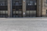 a brick building has many windows with large windows, a black wrought rail, and a white parking sign