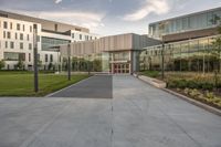 the entrance of a building with a parking lot in front of it, next to several glass walls and a tall pole