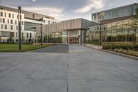 the entrance of a building with a parking lot in front of it, next to several glass walls and a tall pole