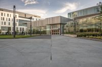 the entrance of a building with a parking lot in front of it, next to several glass walls and a tall pole