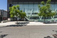 large glass building on side of street with parking lot in foreground next to street