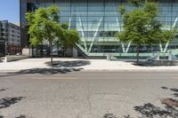 large glass building on side of street with parking lot in foreground next to street