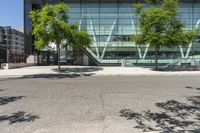 large glass building on side of street with parking lot in foreground next to street