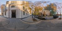 a photo taken from a fisheye lens of a street in front of buildings with two parked cars