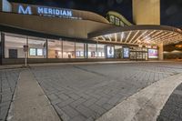 the entrance to the metro at night with lights on and parked car in the driveway