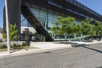 a road is next to a building near a street corner and some trees are in front