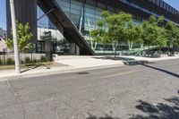 a road is next to a building near a street corner and some trees are in front