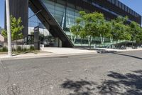 a road is next to a building near a street corner and some trees are in front