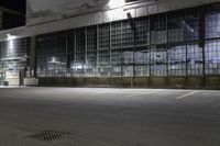 a night shot of a empty warehouse building and parking lot, with an empty road passing under it