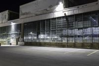 a night shot of a empty warehouse building and parking lot, with an empty road passing under it