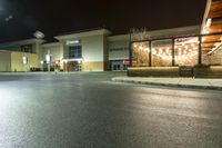 this is a parking lot at night with lights shining on the building and sidewalk in front of it