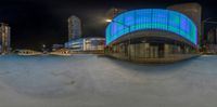 the camera is being reflected on a modern building at night in an urban area with city buildings