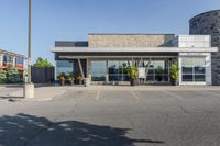 the parking lot of a building with a bunch of bushes outside of it's windows