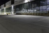 a big building with an empty parking lot at night time, on which cars are parked